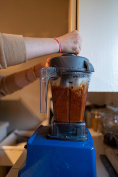 Blue blender filled with spicy red harissa pepper ingredients