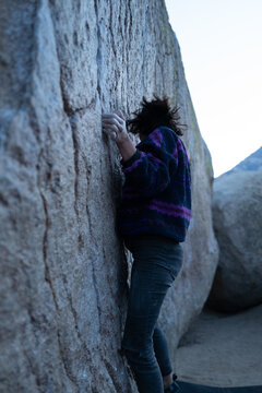 Rock climber starts to climb large boulder