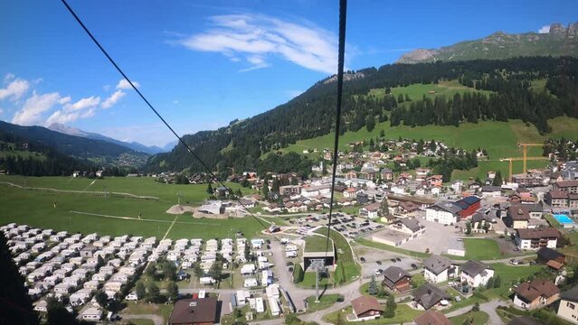 Cable car ride in Switzerland. The cable car descends into the valley. You can see the small village in the valley and the beautiful nature of Switzerland with its hiking trails. Grisons Churwalden