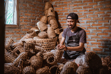 Water hyacinth craftsman man making baskets in village against brick wall background - obrazy, fototapety, plakaty
