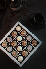 Handmade chocolate candies. Vertical photo on a dark background. Handmade candies in square box.Flat lay.Top view.