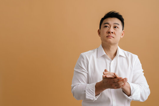 Brunette Asian Man Wearing Shirt Rubbing His Hands And Looking Aside