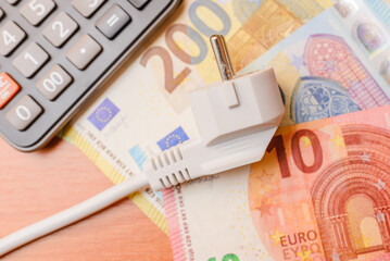 Electric Plug,euro banknotes,calculator flat laying on the table.The concept of rising electricity prices.Top view.