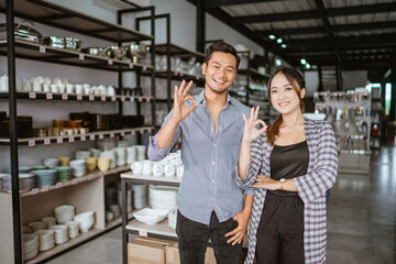 Asian man and woman standing with okay hand gesture at home appliance store