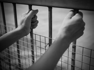 Hand woman holding prison steel  black and white photography. alone  person behind jail cage. for...
