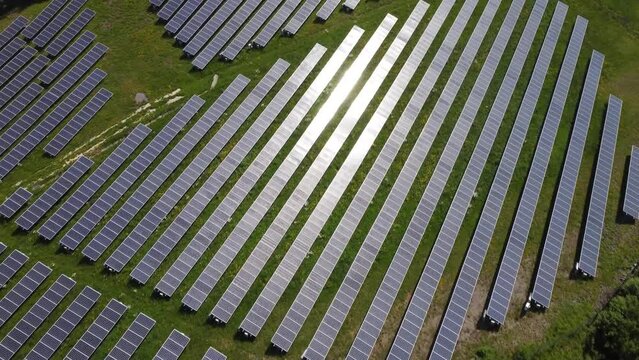 Aerial view of solar energy photovoltaic powerplant with reflection of sun in panels