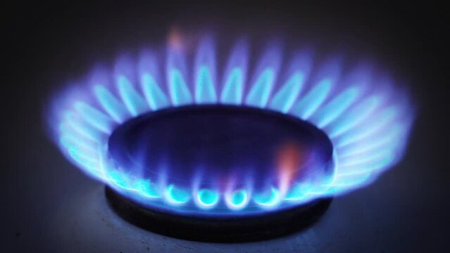 Gas Burner Burning On A Gas Stove And Turning Off In The Dark. Blue And Yellow Flame On A Stove.