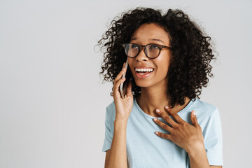 Black curly woman wearing eyeglasses smiling and talking on cellphone