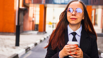 Smiling female entrepreneur drinking coffee to go on street