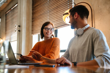 White young colleagues using gadgets while working together in office