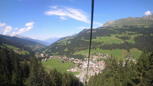 Cable car ride in the canton of Grisons. The gondola lift descends into the valley. You can see the small village in the valley and the beautiful nature of Switzerland