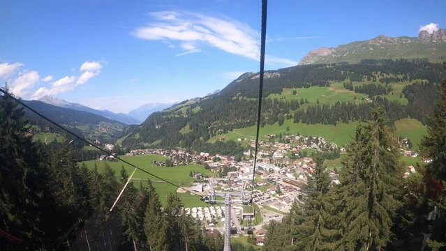 Cable car ride in Switzerland. The cable car descends into the valley. You can see the small village in the valley and the beautiful nature of Switzerland with its hiking trails