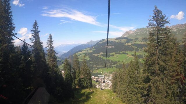 Cable car ride in canton Grisons Churwalden. View from a cable car on the beautiful nature in Switzerland. The gondola lift descends into the valley. The small village can be seen