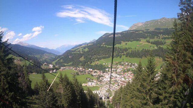 Cable car ride in the canton of Grisons. The gondola lift descends into the valley. You can see the small village in the valley and the beautiful nature