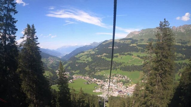 Cable car ride in canton Grisons Churwalden. View from a cable car on the beautiful nature in Switzerland. The gondola lift descends into the valley. You can see masts of the cable railroad