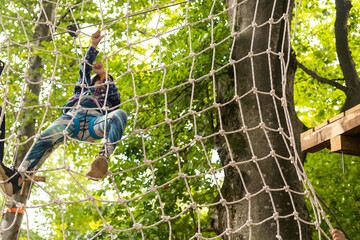 Adorable little girl enjoying her time in climbing adventure park on warm and sunny summer day.