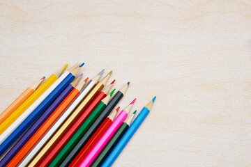 明るく茶色い机の上の沢山のカラフルな色鉛筆