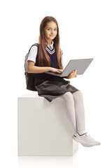 Smiling little schoolgirl sitting with a laptop