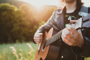 Man playing acoustic guitar in nature on a sunny day