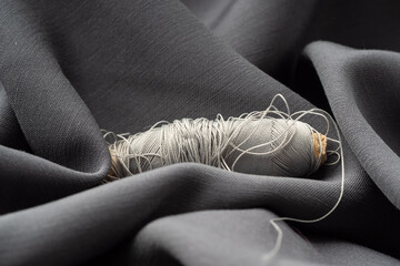 A reel with gray threads in a draped soft fabric, close-up, macro. Atelier, tailoring, sewing...