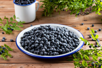 Frozen blueberries in a metal bowl on wooden table