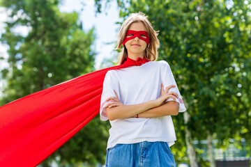 Funny teenager girl playing power super hero over green park background