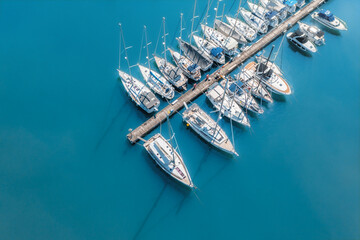 Top view from drone of sailboats and various speed boats in dock. Aerial view of luxure yachts and motorboats moored in a port with clear blue water in summer. Pula, Croatia - Powered by Adobe