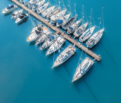 Aerial view of luxure yachts and motorboats moored in a port with clear blue water in summer. Top view from drone of sailboats and various speed boats in dock. Pula, Croatia