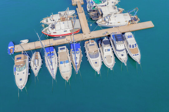 Top view from drone of sailboats and various speed boats in dock. Aerial view of luxure yachts and motorboats moored in a port with clear blue water in summer. Pula, Croatia