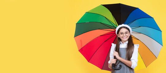 happy teen girl in glasses under colorful umbrella for rain protection in autumn season. Child with autumn umbrella, rainy weather, horizontal poster, banner with copy space.