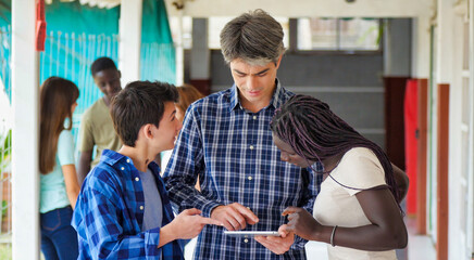 Teacher in the school hallway discussing with his teenager multi ethnic classroom