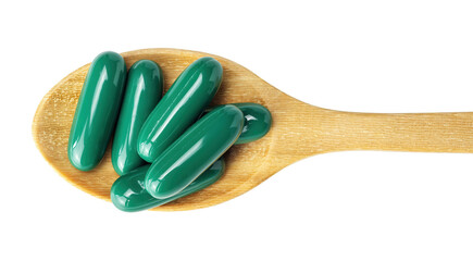 Green capsule pill on a wooden spoon on a white background.