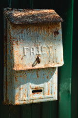 An old green rusty russian postbox with a caption on the metal - for the papes. It is placed on a green metal fence