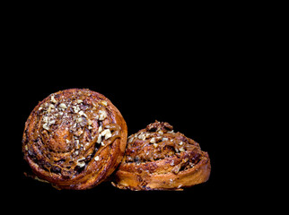  two delicious buns with cream and nuts on a black background.