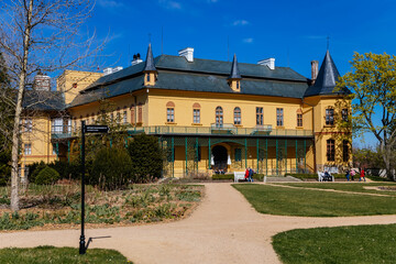 Fototapeta na wymiar Slatinany, Czech Republic, 17 April 2022: classical chateau or romantic yellow castle surrounded by a garden, ancient aristocratic residence with park in summer sunny day