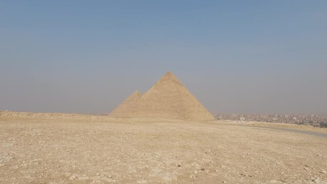 Panning view of Pyramid complex with a car passing by with a background of Cairo city. Egypt
