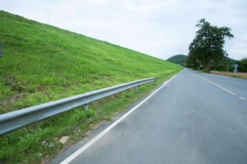 Public road with green grass on the side and the mountains in the back view