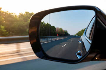 Look in the rear view mirror of a car. Car driving on the road.
