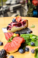 dessert cake on a black slate on a table served with berries
