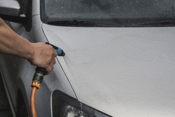 The process of rubbing the hood on a passenger car. Silver car wash
