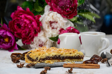 dessert apple pie on a black slate on a background with flowers
