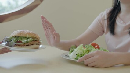 Woman on dieting for good health concept. White women choose for vegetable salad and rejected hamburgers. Weight loss court to reduce starchy and junk food.