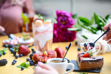 many tasty desserts on the table with female hands in a macro shot
