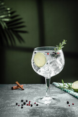 Gin tonic cocktail and shadows next to the window  on dark concrete background. Vertical format.