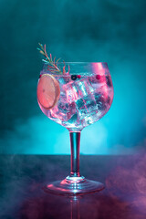 Cold gin and tonic under pink and blue light illumination on smoky background with copy space. Vertical format. - obrazy, fototapety, plakaty