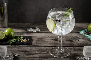 Cold glass of gin tonic with ice on dark rustic background .