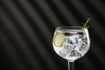 Close-up of gin tonic cocktail  with shadows and copy space.