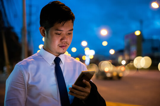 Young Man Walking And Chatting On Mobile Phone With Friends At Social Networks Outdoor, Portrait Asian Businessman Typing An Sms Message Via Smartphone After Work Near Office At Night City Street