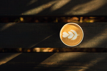 Top view of cappuccino coffee cup on a park bench.