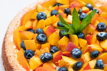 Tasty pie with peaches, blueberries and mint